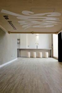 The lowered plywood bed panel seen from below, its Space is (NOT) a luxury lettering facing the empty living area