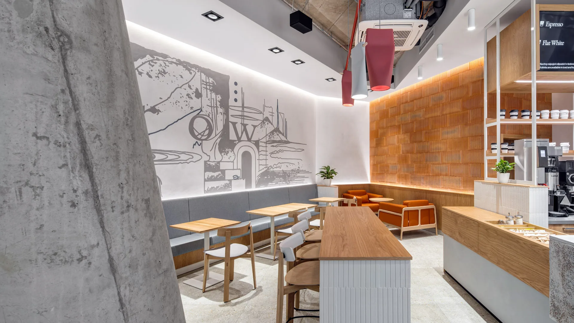 Seating side of Basics Coffee seen past a raw concrete column, with the line-drawn 'grow' mural, backlit terracotta brick wall and light oak bar counter