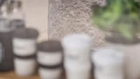 Shelf of branded Basics Coffee takeaway cups against the textured stone counter, shot with a shallow depth of field