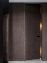 Detail of the full-height dark-stained timber panelling at Black Wood Harmony, with a concealed door left ajar and warm light spilling through