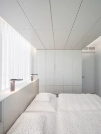 Second bedroom at Black Wood Harmony finished entirely in pale panelling, with sheer curtains and a low ledge running under the window