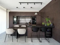 Kitchen island and dining table at Black Wood Harmony, with dark timber cabinetry, black bar stools, a wine fridge and an articulated wall lamp