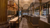 View along the service counter and bar at Masaryčka Restaurant, with communal tables to the left and the historic column in the foreground