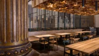 Masaryčka Restaurant seen past a fluted historic column, with the timber ceiling installation and slatted screens framing the tables