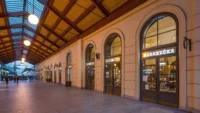Arched shopfronts of Masaryčka Restaurant along the platform hall of Prague's Masarykovo nádraží, under the station's timber roof structure