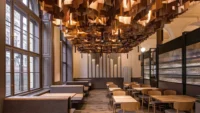 Window side of Masaryčka Restaurant, with banquette seating along the tall historic windows and the illuminated timber ceiling cloud above