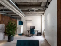 Single work room at Office That Breathes with a teal task chair, a floor lamp and a whiteboard wall covered in sketches