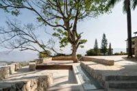 The cafe terrace built around a preserved tree at Bawan Village Visitor Center by TAO