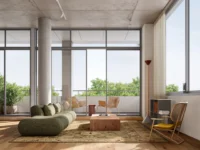 Living room with a round concrete column, a green curved sofa and floor to ceiling windows onto a leafy balcony