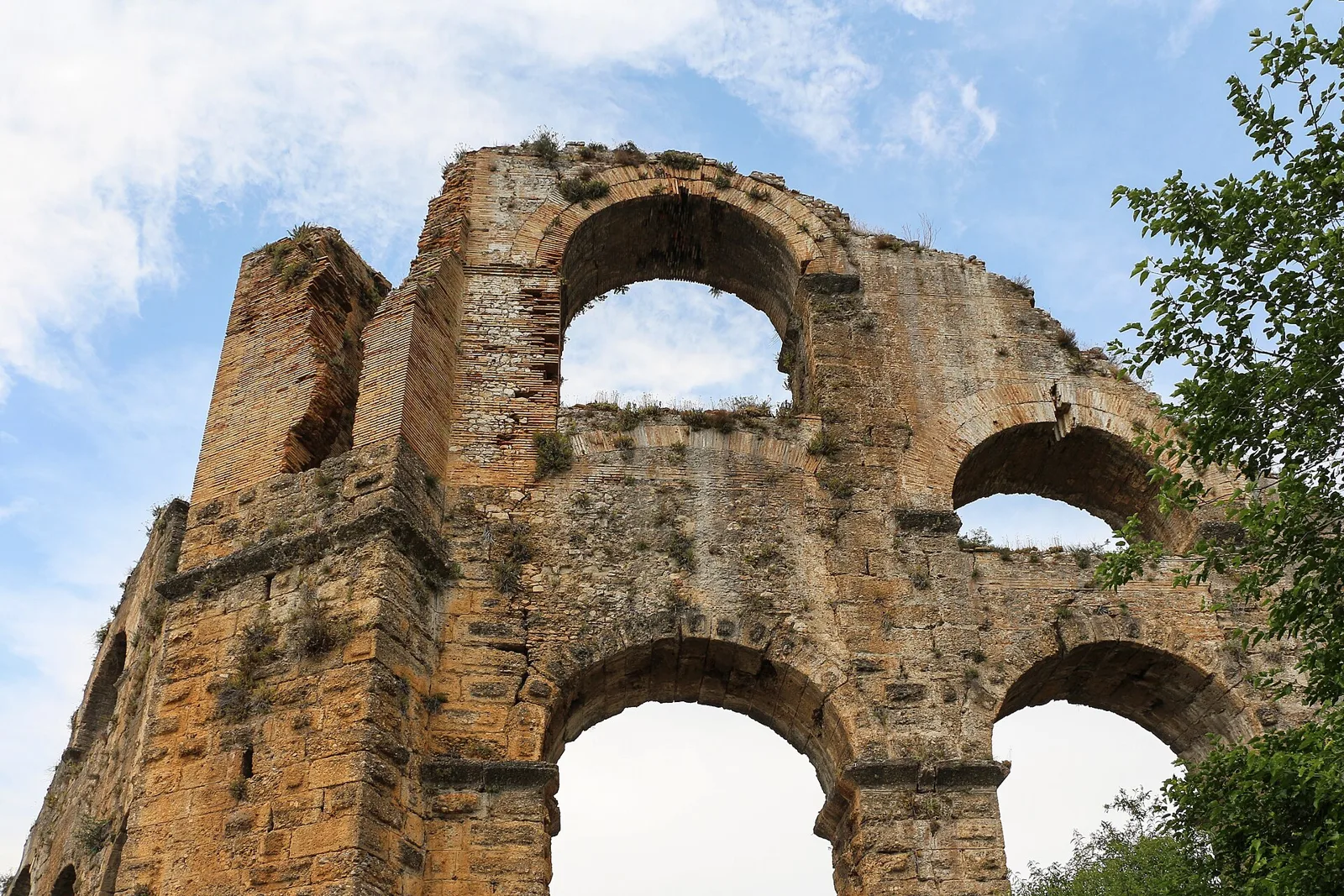 Stone arches of the Roman aqueduct of Aspendos against a cloudy sky