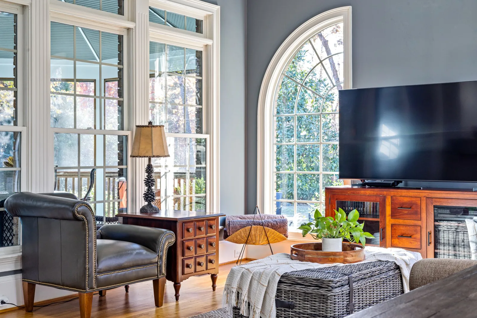 Television on a wooden credenza beside tall arched windows in a living room
