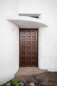 Wooden entrance door set into a curved white rendered wall, Casa d’Abreu Neto by Álvaro Siza