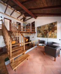 Living and circulation area with a wooden staircase under exposed roof beams, Casa d’Abreu Neto by Álvaro Siza