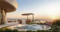 Rooftop terrace with a round plunge pool, shade canopy and loungers facing the sea at sunset
