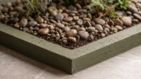 Olive green planter edge filled with river pebbles and ferns