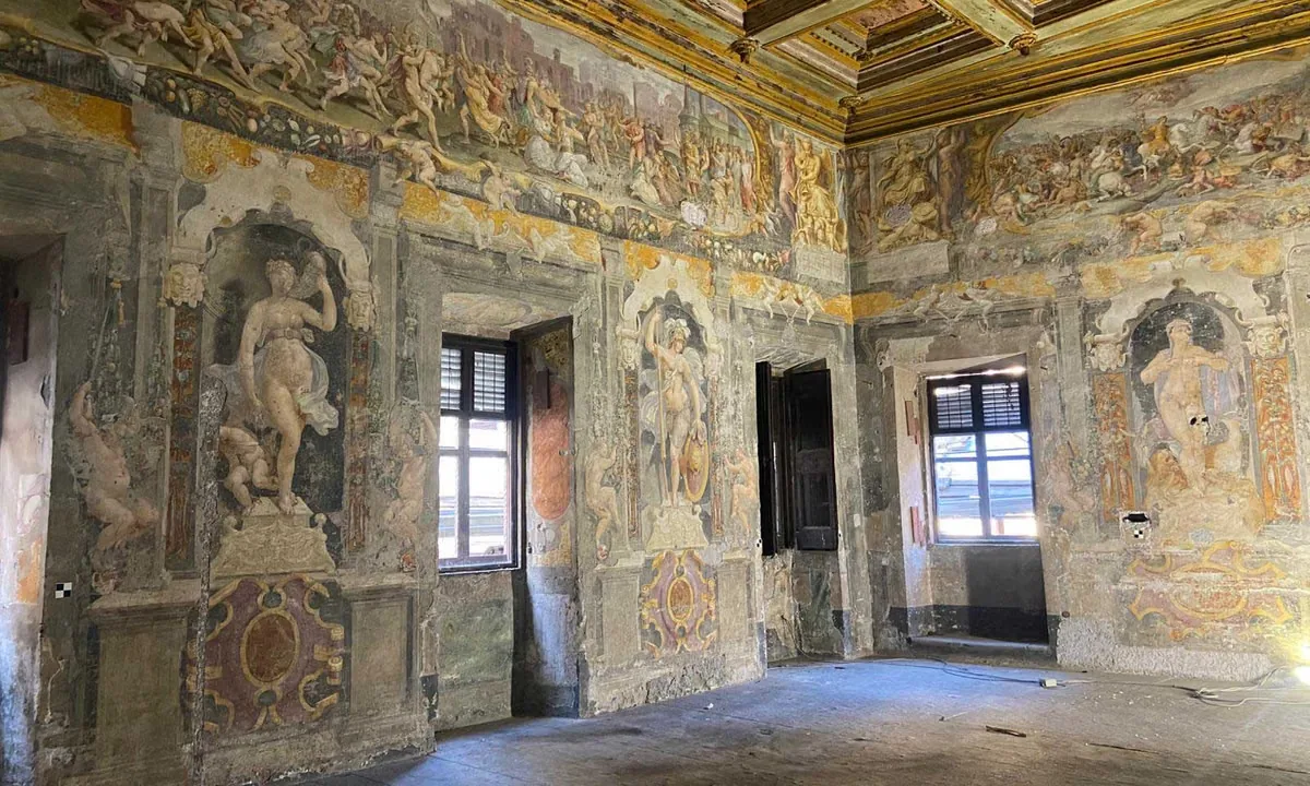 Frescoed room with painted figures in niches, ornate friezes, and a gilded coffered ceiling