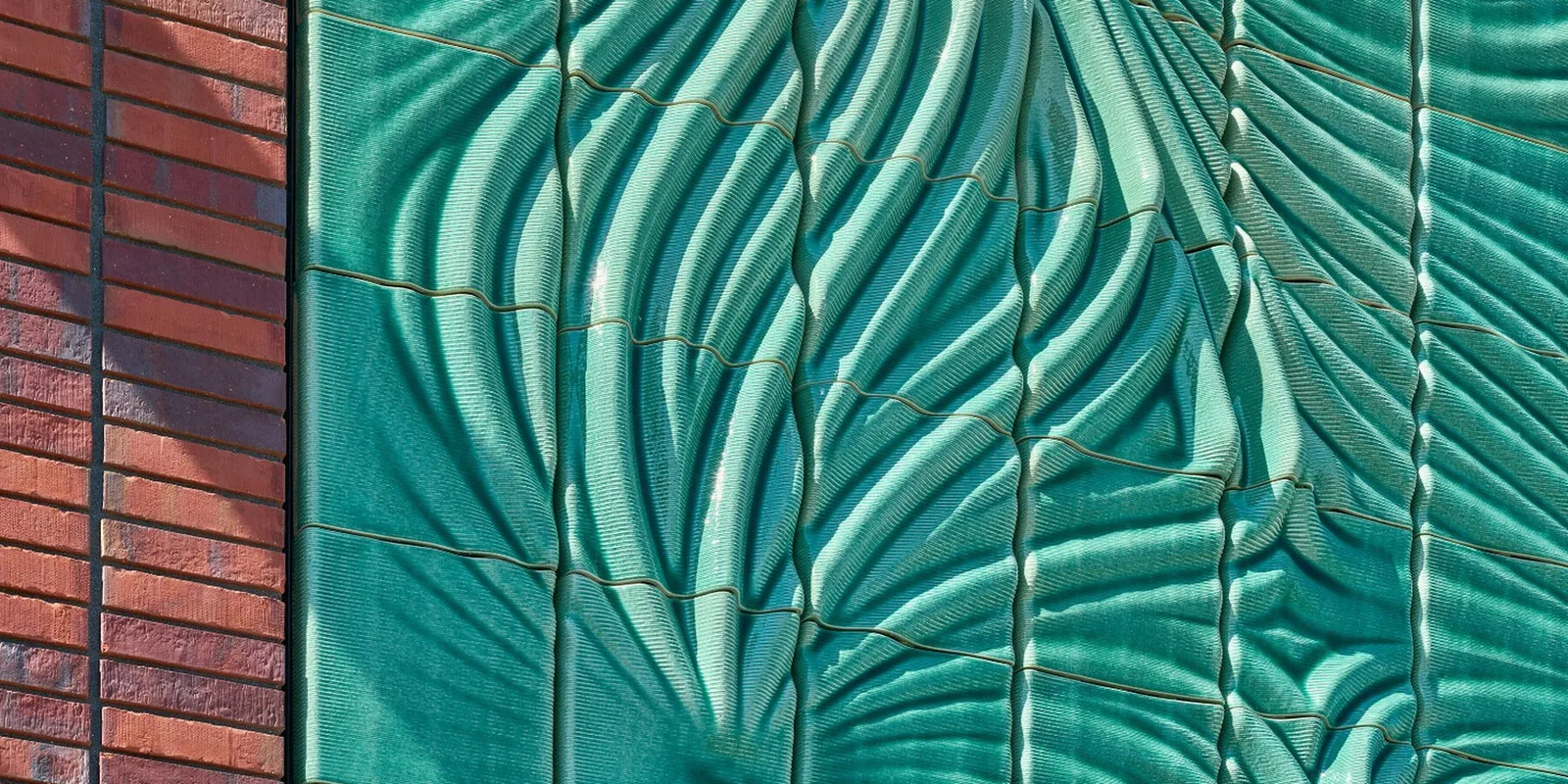 Green glazed ceramic relief meeting the brick pier of the Beverwijk substation