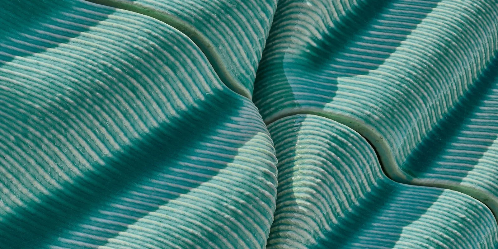 Close up of the ridged ceramic tiles, their lines meeting along a curved seam