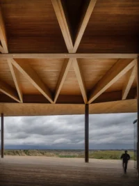 Underside of the timber roof with triangulated glulam trusses over an open deck facing the Badlands