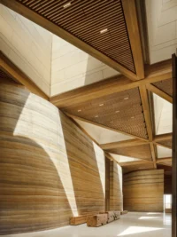Interior hall with rammed earth walls, faceted timber ceiling and skylights drawing daylight down