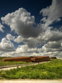 The library seen across grassland beneath towering cumulus clouds