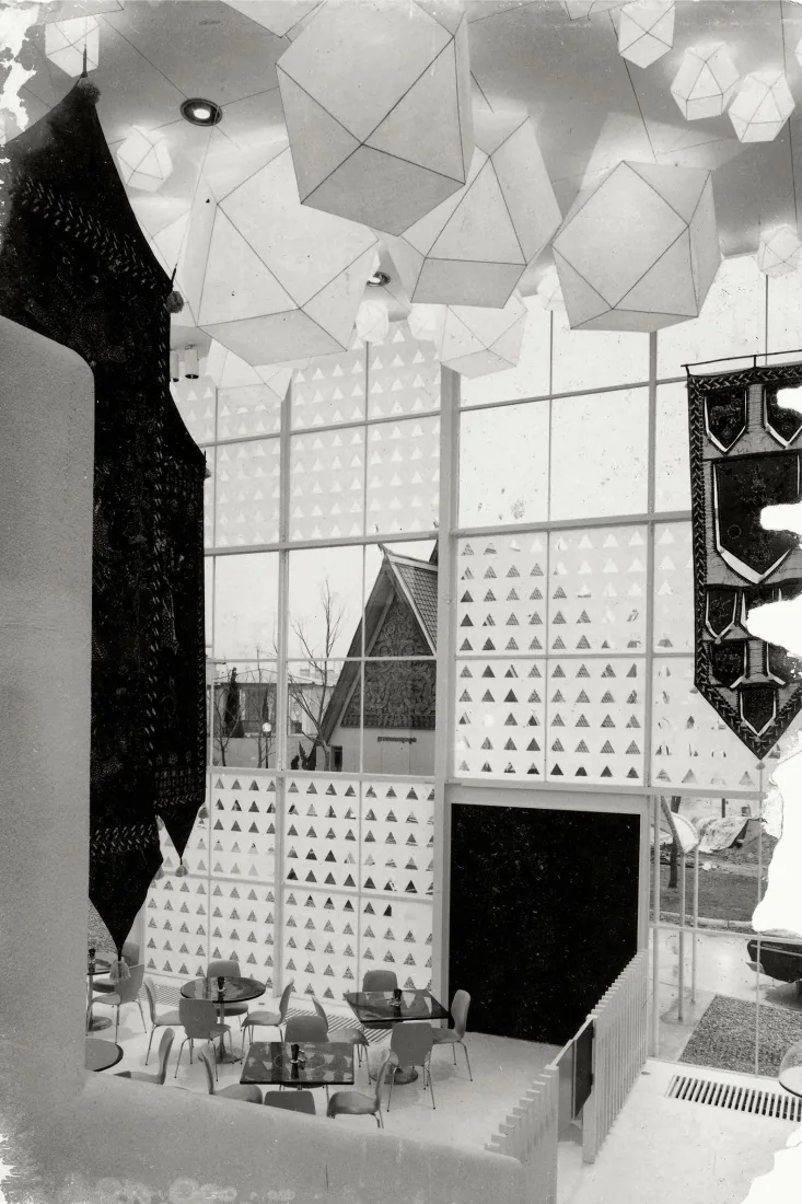 A geodesic-domed room with triangular patterned partitions, patterned tapestries and small tables and chairs