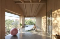 Timber lined room with exposed beams and a full height window looking over trees, Zašová Health Center by AOSI