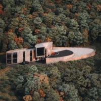 Aerial rendering of the elliptical spiral roof set into the forest, Savan House by Nobico Studio
