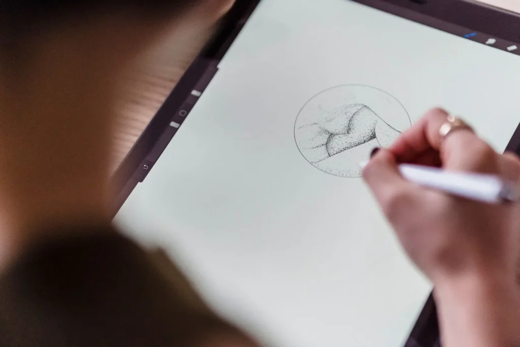 Close view of a hand sketching a small landscape study with a stylus on a tablet screen