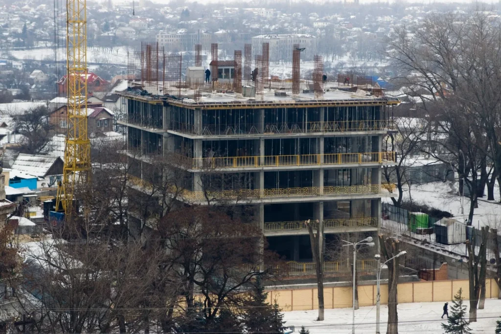 Concrete frame of a multi storey building under construction in a snow covered town with a tower crane