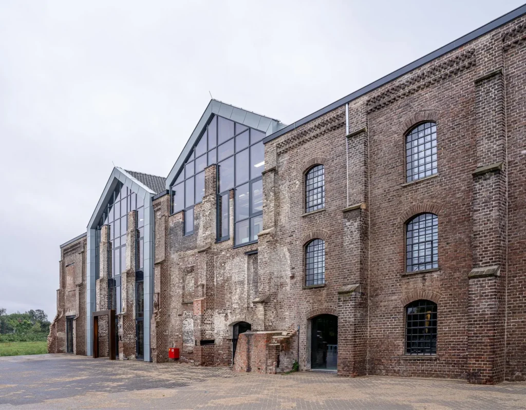 Old brick warehouse extended with a gabled glass volume, an example of adaptive reuse in architecture