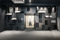 Wall of personal lockers with doors of different sizes and opening directions around a doorway, ADDITIVE HQ by NOA