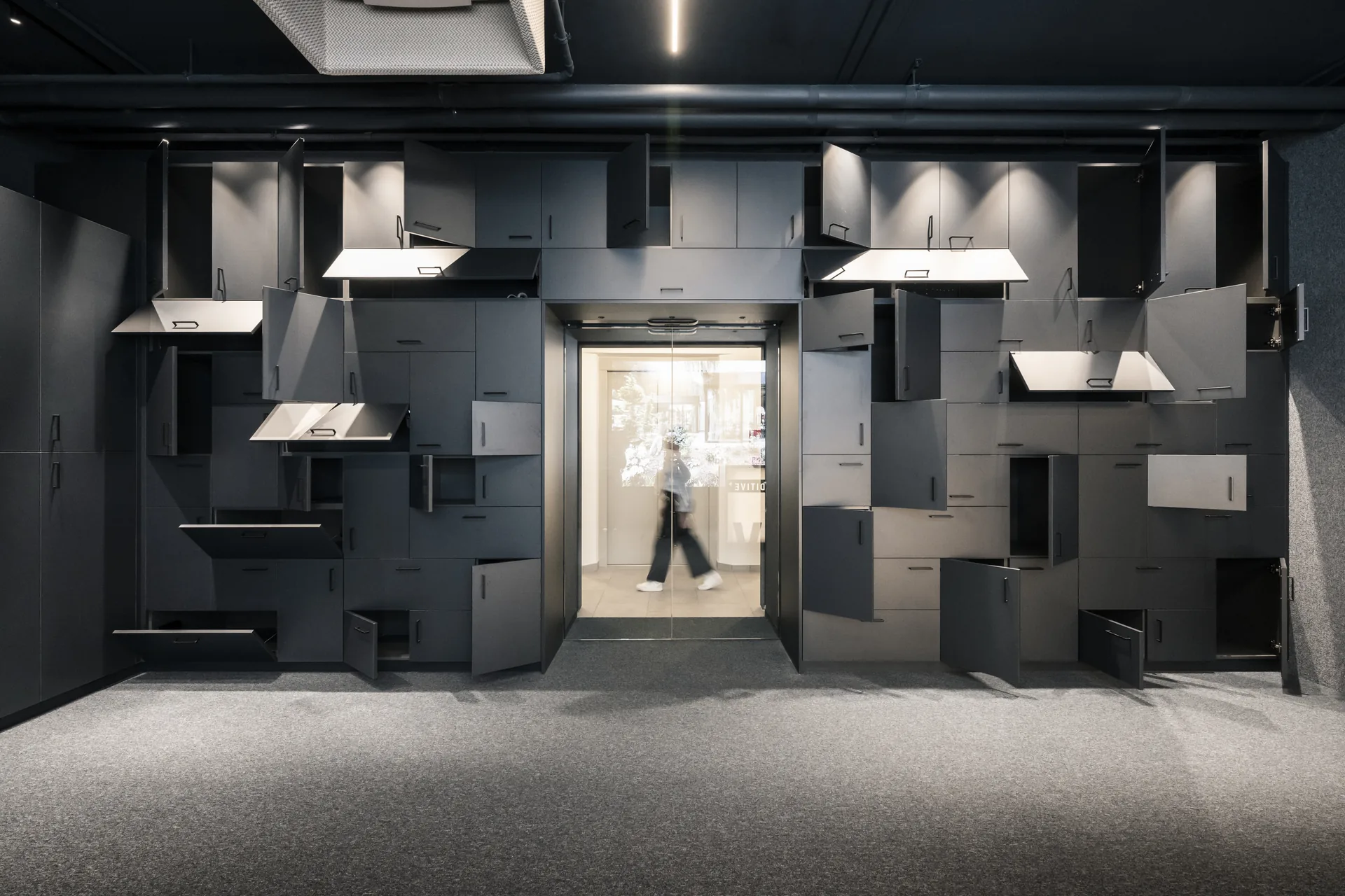 Wall of personal lockers with doors of different sizes and opening directions around a doorway, ADDITIVE HQ by NOA