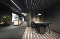 High table in a niche with striped floor and ceiling lines and pendant lights in the communal space, ADDITIVE HQ by NOA