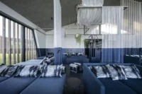 Wellness relaxation room with blue daybeds below and white curtains above the colour line, Aeon by noa*