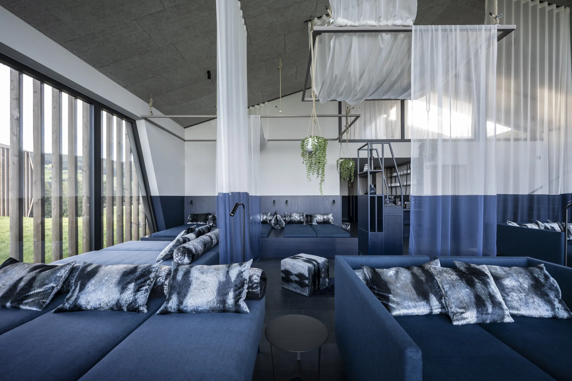 Wellness relaxation room with blue daybeds below and white curtains above the colour line, Aeon by noa*