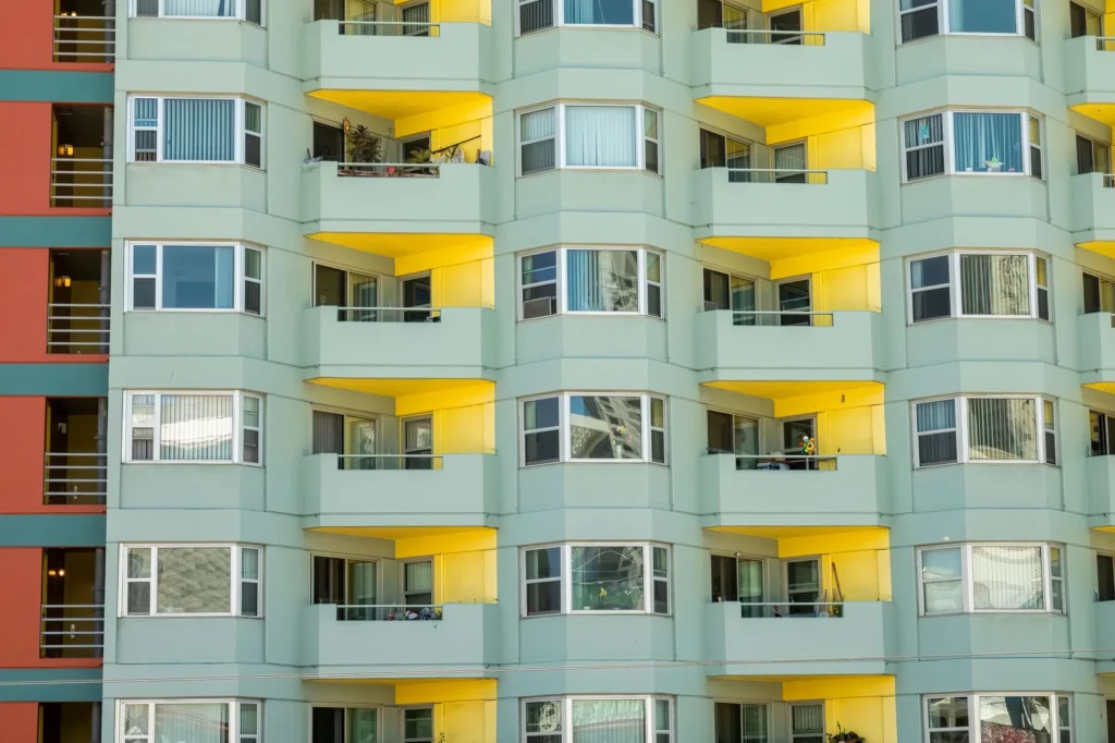 Mint green mid-rise apartment block with stacked yellow balconies and bay windows
