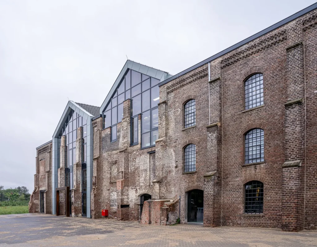 Old brick industrial hall with arched windows and new glazed gables added to its roofline