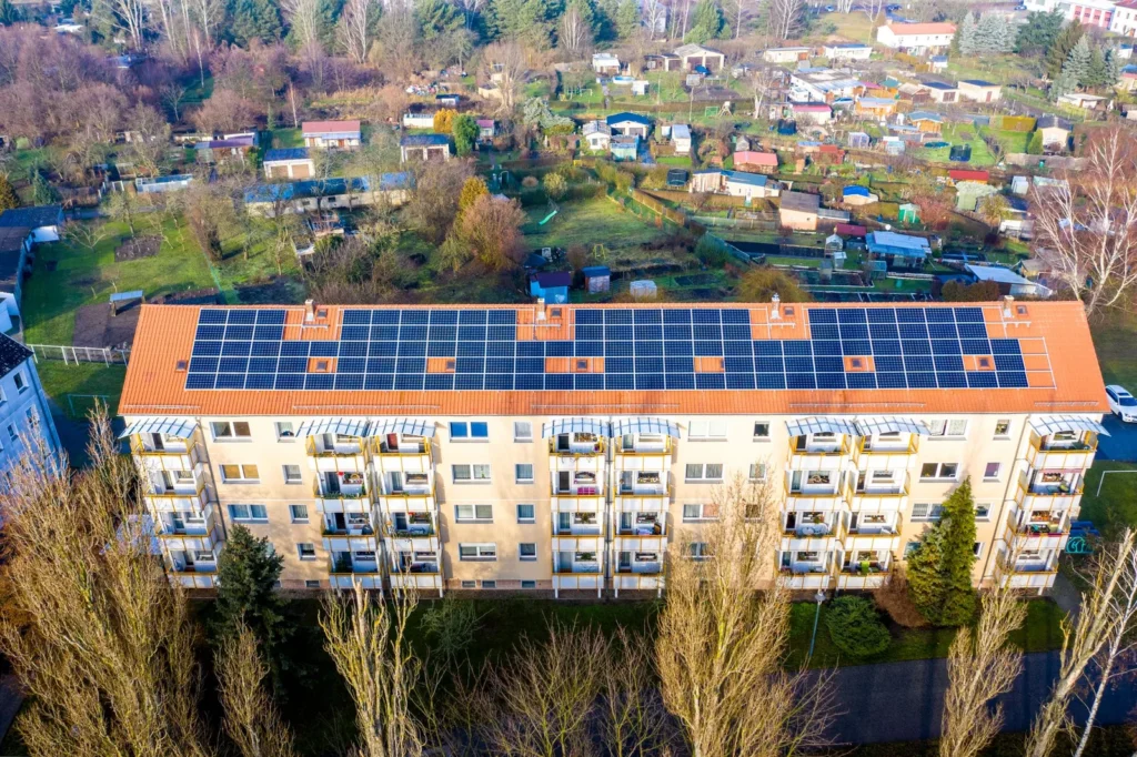Aerial view of an affordable housing design upgrade with solar panels covering the roof of an apartment block