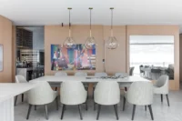 White dining table and pale chairs under glass pendants, Apartment Elache by Caroline Andrusko Arquitetos