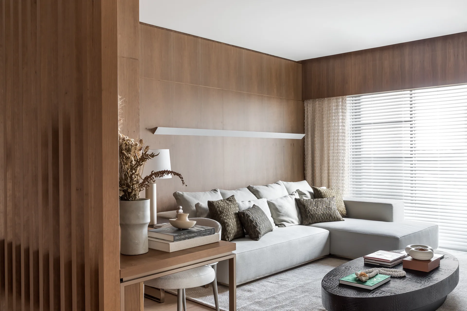 Timber lined sitting room with a corner sofa and a desk, Apartment Elache by Caroline Andrusko Arquitetos