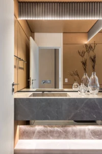 Washroom with a grey stone vanity and a backlit timber ceiling, Apartment Elache by Caroline Andrusko Arquitetos