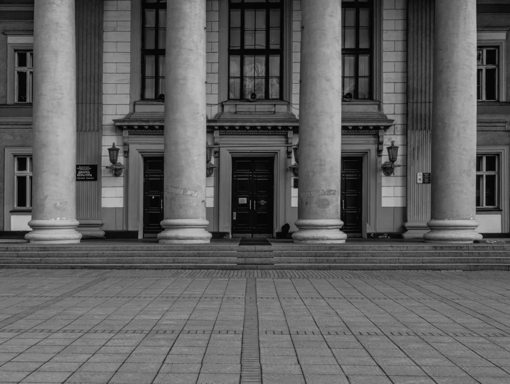 Black and white view of a symmetrical classical facade with a central entrance framed by tall columns, composition in architecture at its most formal