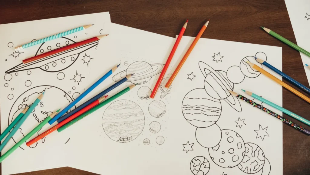 Colored pencils lying on printed line drawing pages, like the pages of an architecture coloring book