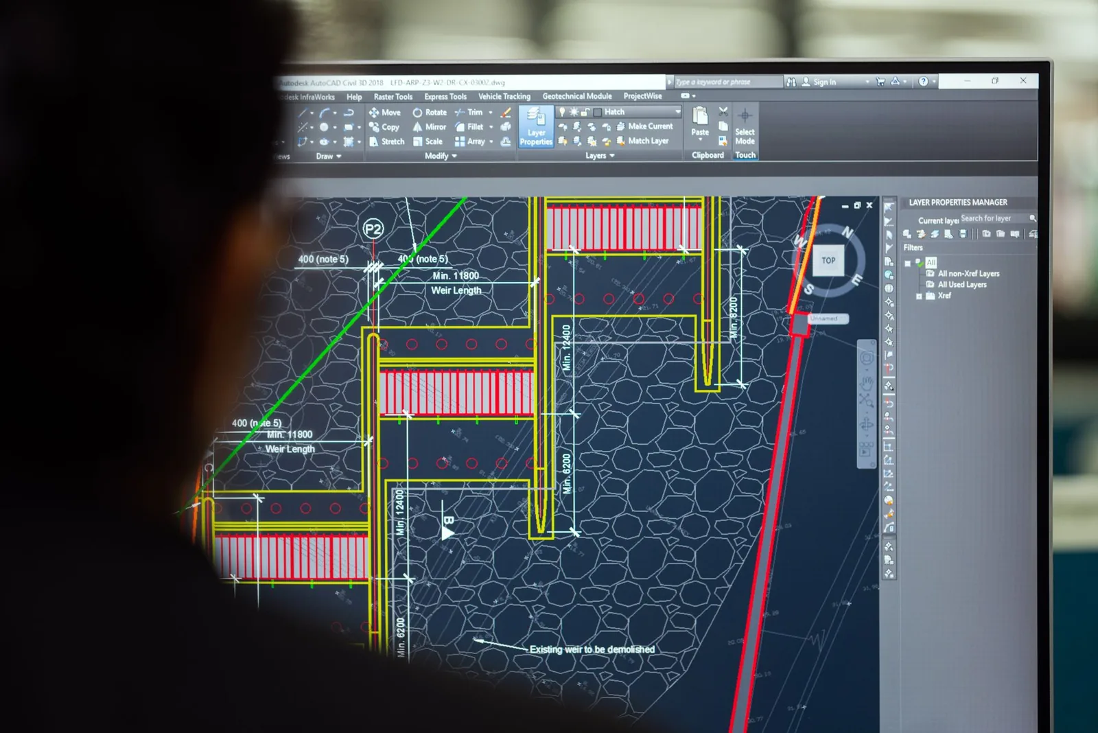CAD drafting software on a monitor showing a detailed technical plan with dimensions, hatching and layers