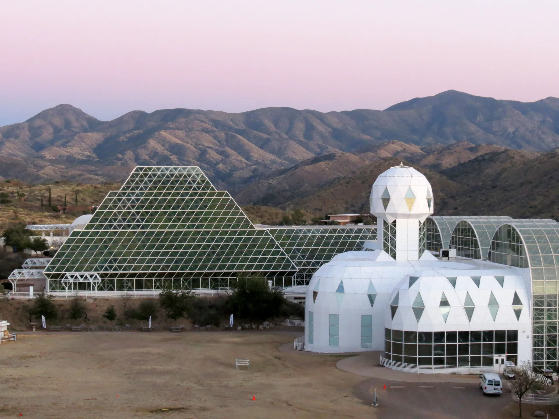 Biosphere 2 in Oracle, Arizona: stepped glass pyramid and white domed habitat tower below desert mountains
