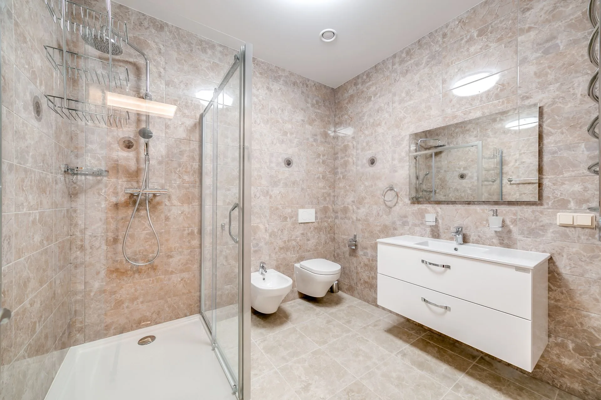 Compact bathroom with a clear corner shower enclosure, wall-hung vanity and stone-look wall tiles