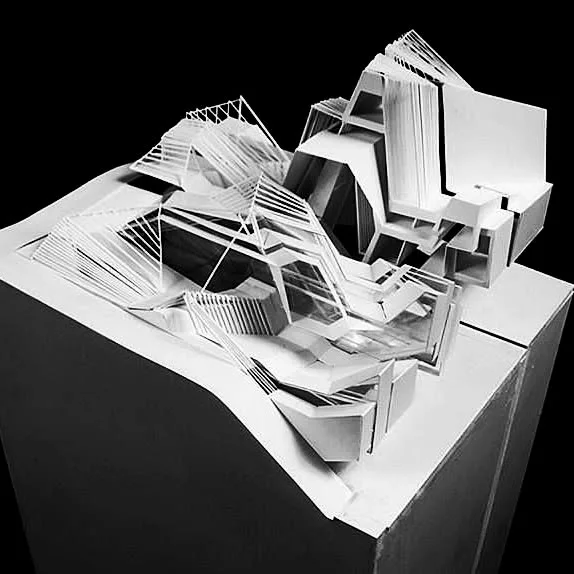 White folded paper concept model of a fragmented building form on a black plinth