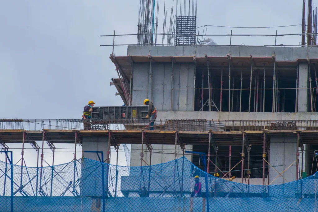 Workers on scaffolding around the concrete frame of a building under construction