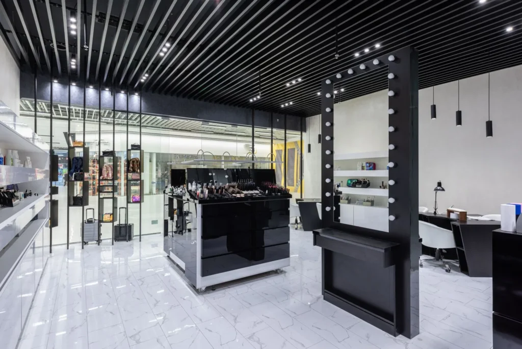Retail interior with slatted black ceiling, track spotlights and a mirror framed with bulbs